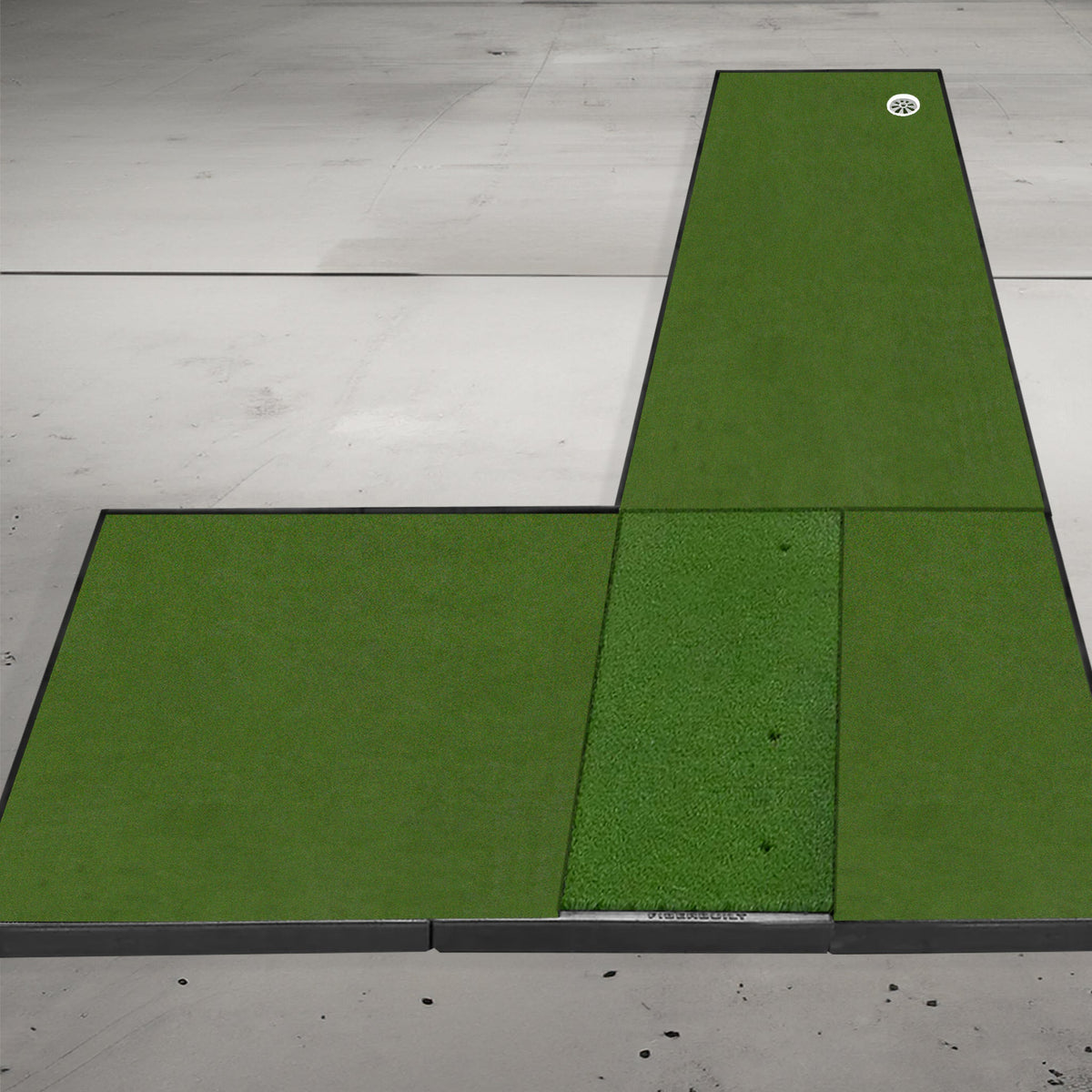 Golf putting mat setup on a concrete floor featuring three green sections, one with a golf ball near the edge.